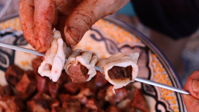 Threading boulfaf liver wrapped in caul fat on Moroccan skewer