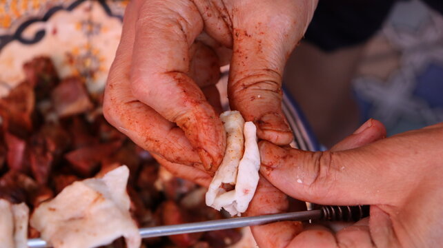 Threading boulfaf liver wrapped in caul fat on Moroccan skewer