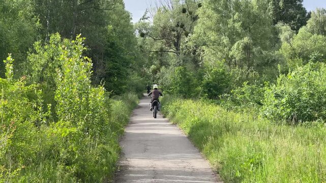 Dirt bike rider on a paved path surrounded by green nature