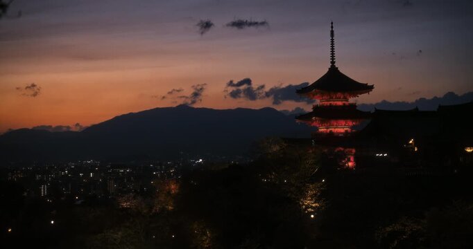 Wide, cinematic shot of silhouetted, glowing Japanese temple at dusk
