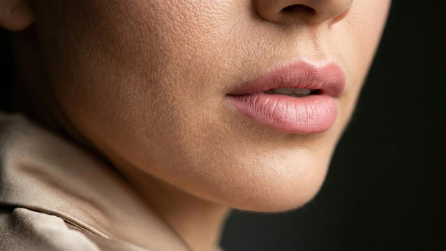 Close-up portrait of a woman's natural pink lips showing detailed skin texture and fine hairs.