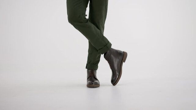 Stylish man walking and dancing in leather boots on an isolated white background, showcasing his fashion and movement
