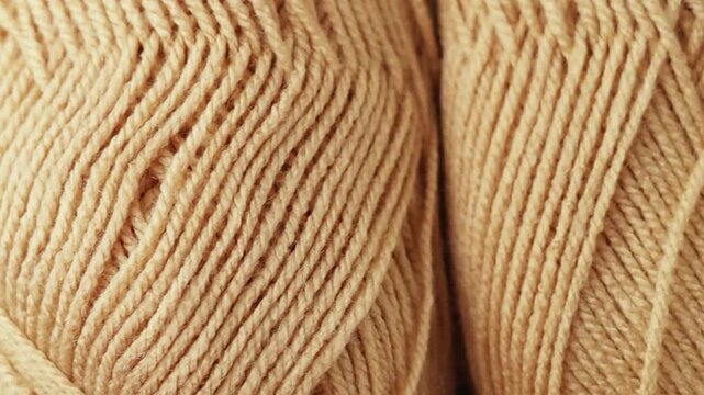 Extreme close-up panning shot across tightly wound beige yarn skeins. Detailed texture of natural wool threads, perfect for crafting backgrounds, textile design, and cozy lifestyle concepts.
