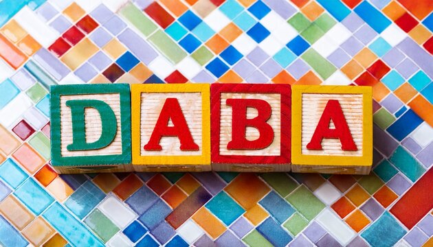 colorful wooden alphabet blocks spelling daba on mosaic background