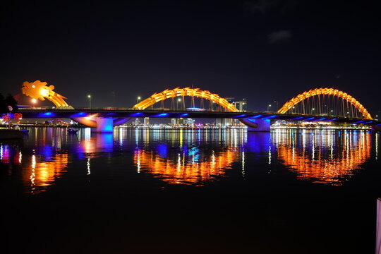 Dragon Bridge illuminated at night with colorful water reflections in Da Nang Vietnam