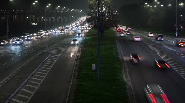 Timelapse of an evening Kyiv highway in the city center, cars moving with headlights on, speedlight