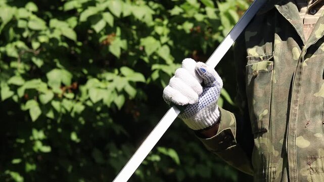 Garden pruner (long-handled pruner), in the hands of a gardener close-up. The tool is designed for pruning high branches and wilted shoots. Hands in gloves with telescopic garden pruners
