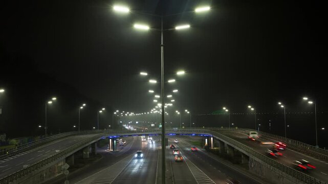 Timelapse of evening traffic in Kyiv's city center near the bridge, cars moving with headlights on, speedlight