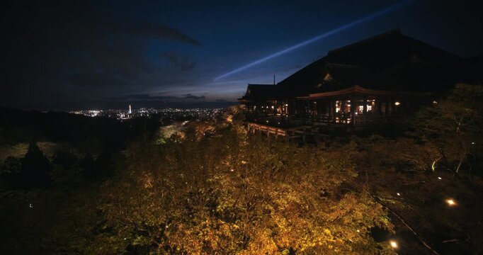 Silhouette of majestic, ancient Japanese temple on hill with view of city at dusk