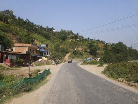 Scenic mountain highway passing through hilly terrain with vehicles traveling along a dusty road construction section.