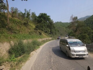 Fototapeta premium Scenic mountain highway passing through hilly terrain with vehicles traveling along a dusty road construction section.