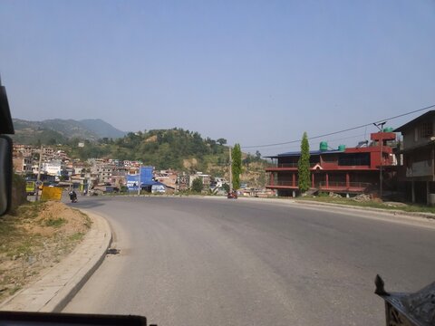 Scenic mountain highway passing through hilly terrain with vehicles traveling along a dusty road construction section.
