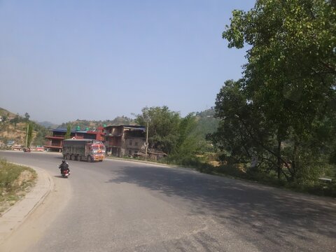 Scenic mountain highway passing through hilly terrain with vehicles traveling along a dusty road construction section.