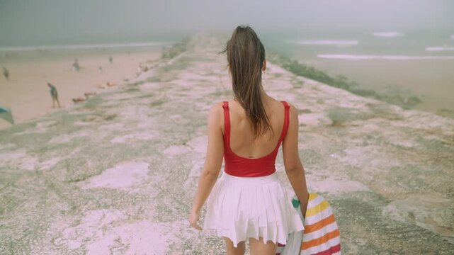 Female figure in swimwear enjoying walk along jagged oceanfront coast