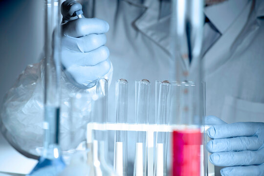 Gloved hands handling pharmaceutical samples results in lab, drug testing and quality control with chemical glassware and solutions.