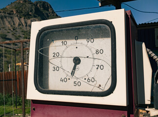 Vintage fuel pump display with broken glass dial on a sunny day in a rustic mountain area © Evgenii Bakhchev