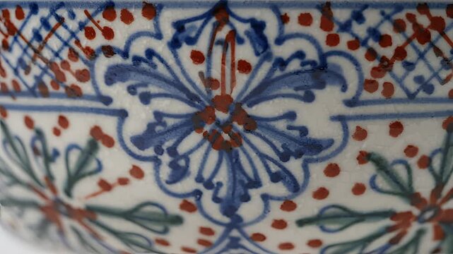 Closeup of intricately painted ceramic bowl with blue and red floral patterns.