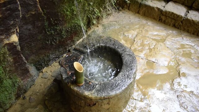 Water flowing from a natural creek and getting collected in a urn 