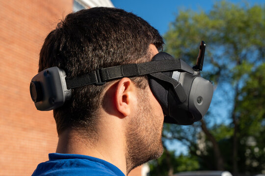 Horizontal photo of a man wearing FPV goggles while controlling a drone, showcasing immersive first-person flight experience, modern aerial technology, and advanced drone piloting