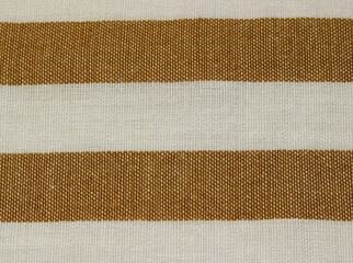 Fototapeta premium Close up of wrinkled classic light brown and white horizontal striped fabric. Texture of crumpled caramel color striped polyester cloth background.