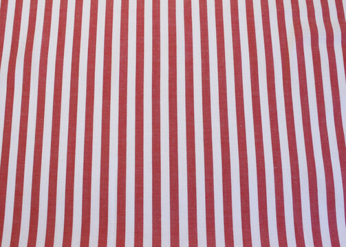 Texture of red vertical striped cotton cloth background. Close up of classic red and white striped fabric. 