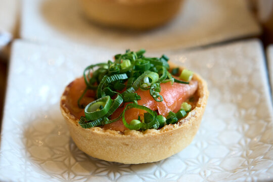 Smoked salmon quiche topped with fresh chopped scallions close-up.
