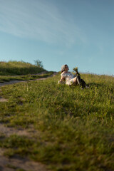 Naklejka premium Child joyfully rests in a sunny green meadow while holding wildflowers on a serene afternoon in nature