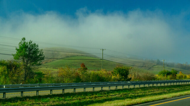 Tennessee, USA. A rural countryside scene with rolling green hills partially obscured by a thick blanket of morning fog.