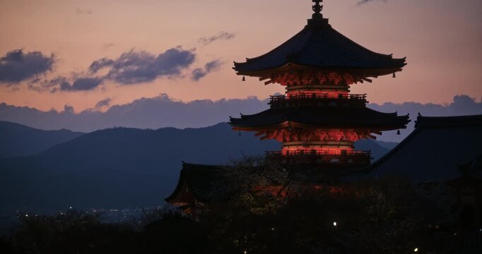 Cinematic, silhouetted medium shot of ancient Japanese temple tower at dusk