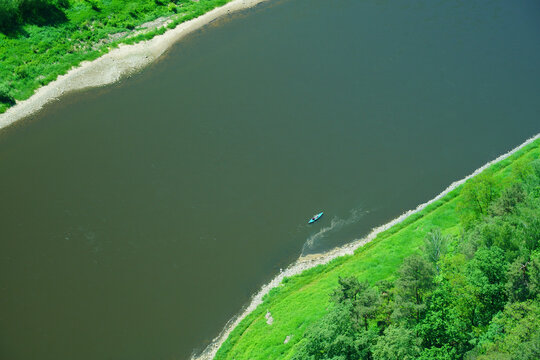 Aerial view of a lone blue kayak paddling down the Elbe River winding through Saxon Switzerland, Germany
