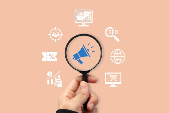 Digital marketing concept with magnifying glass highlighting megaphone icon surrounded by SEO, ecommerce, analytics, advertising, sales, and online business symbols