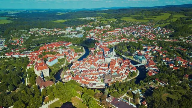 Aerial panorama of a historic medieval riverside town with terracotta roofs, castle complex and church spire
