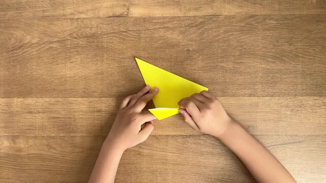 Child Hands Folding Yellow Origami with Adult Holding Corner in 4K Slow Motion