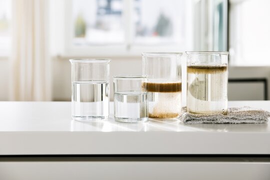 Beakers and jars with clear and muddy water on kitchen counter during daytime