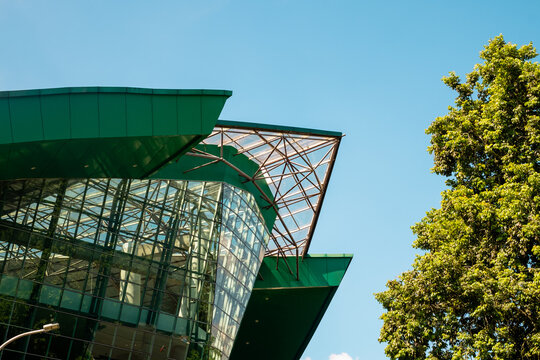 A unique contemporary glass architecture of university graduation building in Jember Indonesia with green summer foliage and blue sky background during summer.