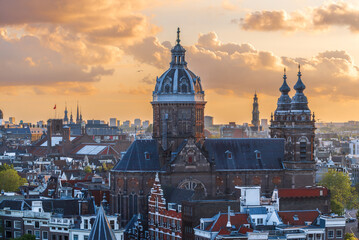 Obraz premium Amsterdam cityscape with St. Nicholas Basilica at sunset, aerial view of historic city center roofs, Netherlands