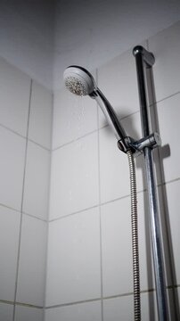 03 October 2025 Germany Munich. Chic Tiled Corner With Droplets. Updated Bathing Area With Flexible Hose And Adjustable Rail. Contemporary Bath Space Showcasing Elegant Tiling And Water