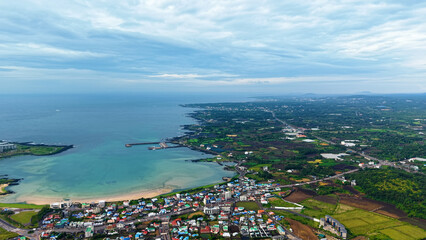 Fototapeta premium Aerial drone view of Seongsan Ilchulbong coastal village farmland and ocean landscape in Jeju Island South Korea