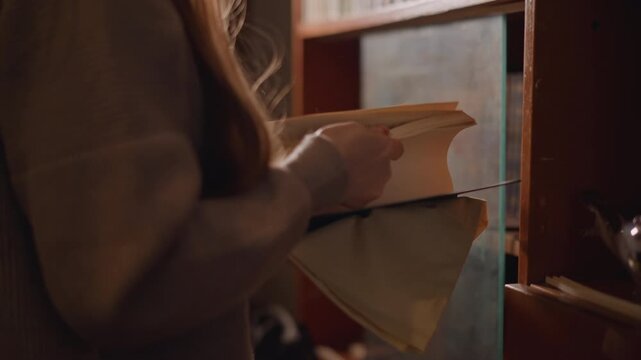 Archivist carefully reviews yellowed papers. Closeup of woman sorting aged history files. Focused female librarian services old archive papers with attentive care under warm lamp lighting