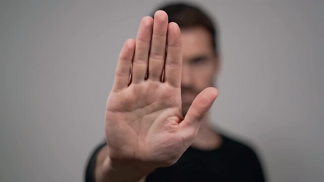 Man's Hand in Stop Gesture with Blurred Face