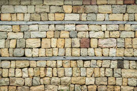 Full frame rustic stone wall texture with wooden beams, natural masonry background for architecture and design.