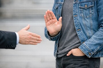 Fototapeta premium Two men in different attire shake hands, symbolizing a deal or agreement