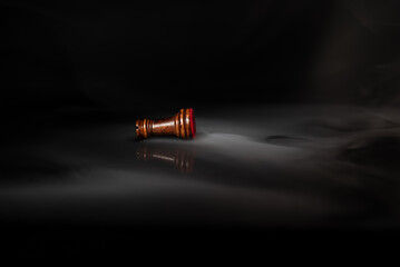 Fallen chess rook surrounded by smoke on a dark background, symbolizing defeat, exhaustion, rivalry, failure, pressure, strategic loss and psychological or business challenges. © Artur