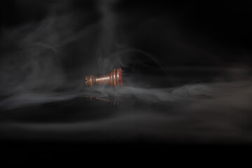 Fallen chess rook surrounded by smoke on a dark background, symbolizing defeat, exhaustion, rivalry, failure, pressure, strategic loss and psychological or business challenges. © Artur