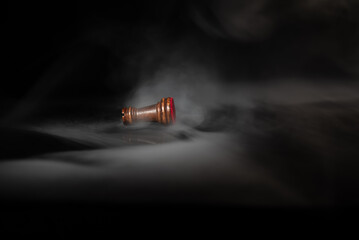 Fallen chess rook surrounded by smoke on a dark background, symbolizing defeat, exhaustion, rivalry, failure, pressure, strategic loss and psychological or business challenges. © Artur