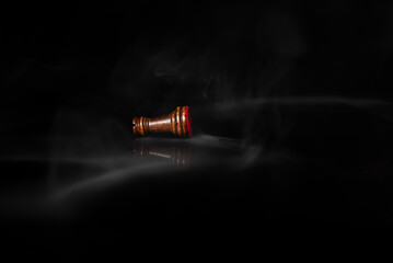 Fallen chess rook surrounded by smoke on a dark background, symbolizing defeat, exhaustion, rivalry, failure, pressure, strategic loss and psychological or business challenges. © Artur