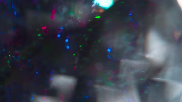 Facets of the Diamond Glow in the Dark. The light passes through the facets of a slowly rotating diamond and creates repetitive sparkling highlights and rainbow colors