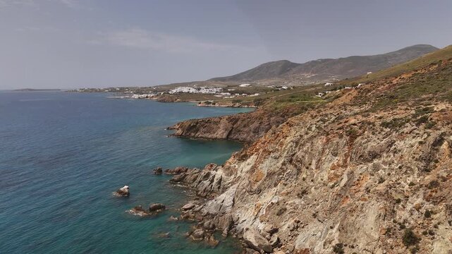 4K drone tracking down and right along the rugged cliffs of Kalogeros Beach, Paros, Greece