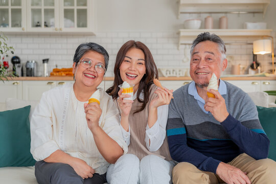 Happy Asian family taking a selfie with smart phone and ring light inside home kitchen concept for social media photo digital influencer technology marketing lifestyle happiness
