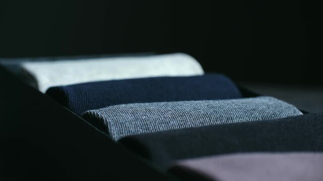 Close up drawer organizer with colorful, soft cotton socks neatly folded arranged in row, showing tidy and organized closet concept with focus on comfortable apparel. Colorful rolled socks.